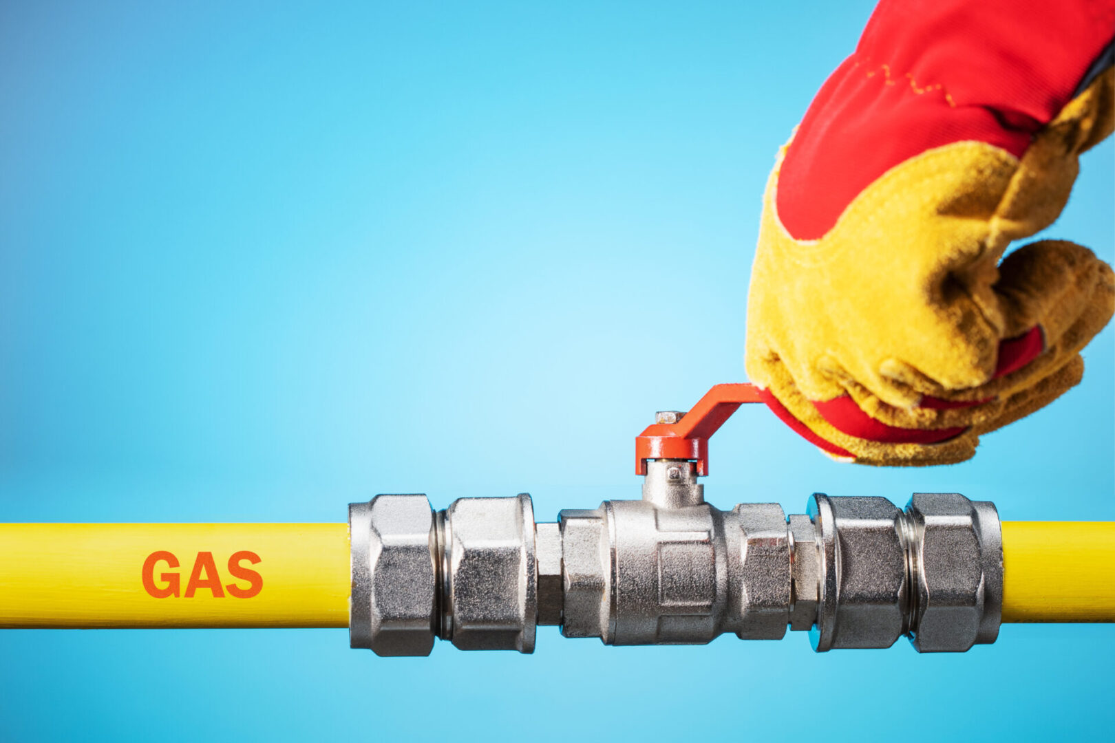 Opening or closing the gas pipeline gate. Male hand in yellow glove  opens or closes gas valve on gas pipe. Copy space.