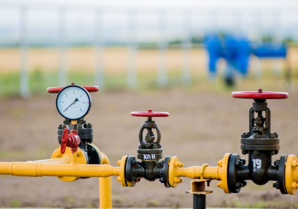 Red faucet with steel pipe in natural gas treatment plant in bright sunny summer day