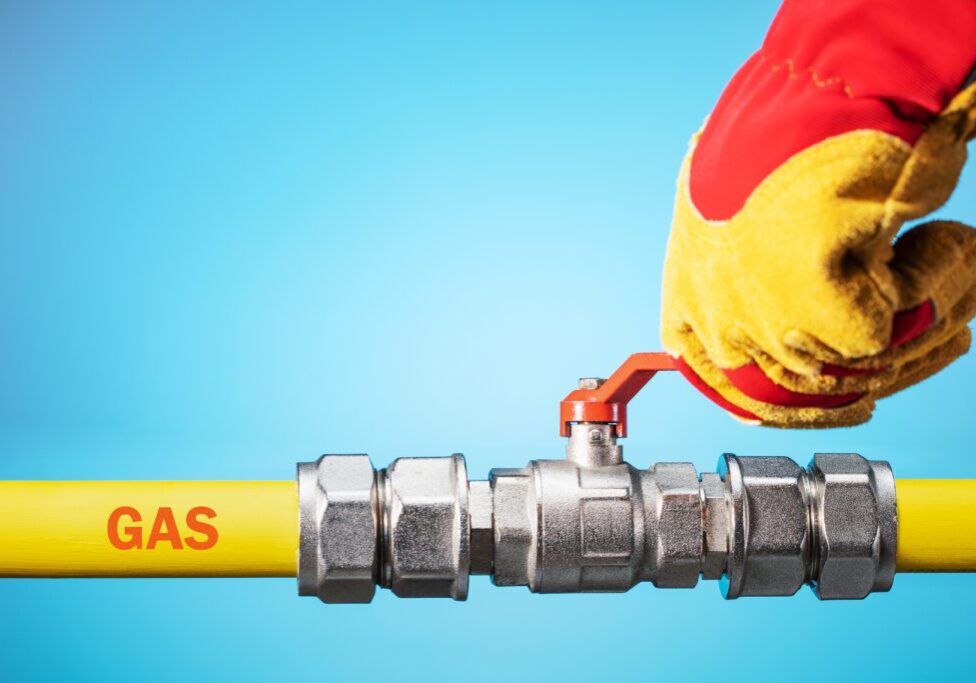 Opening or closing the gas pipeline gate. Male hand in yellow glove  opens or closes gas valve on gas pipe. Copy space.