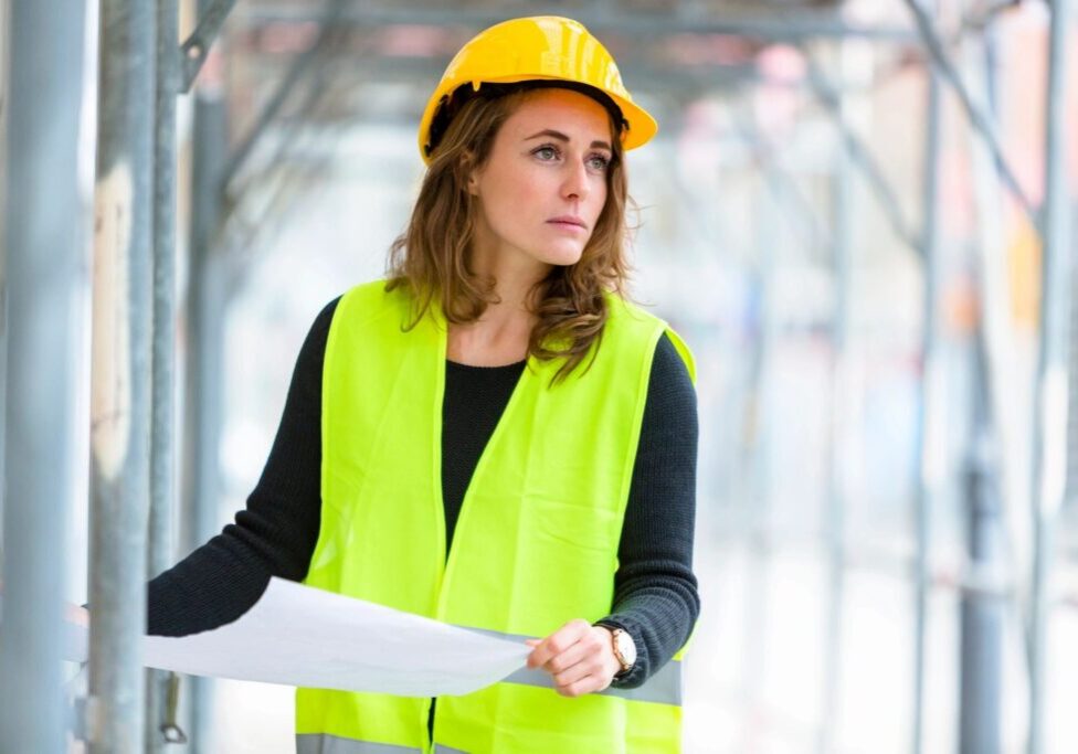 Image of a female with a hard hat on looking at construction plans